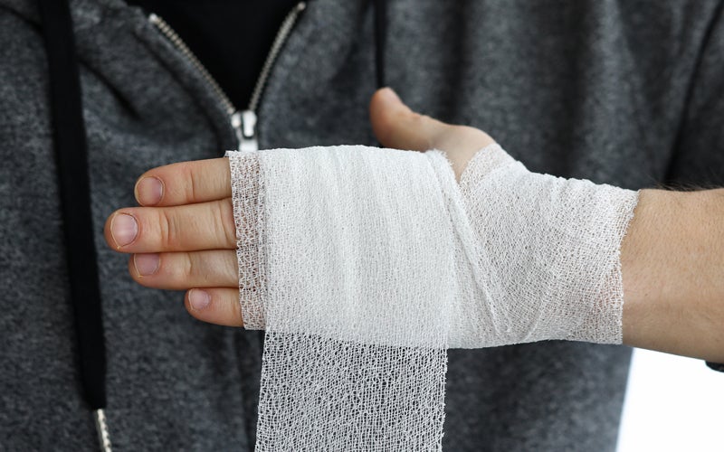 Hand wrapped in white gauze bandage, with more gauze dangling.