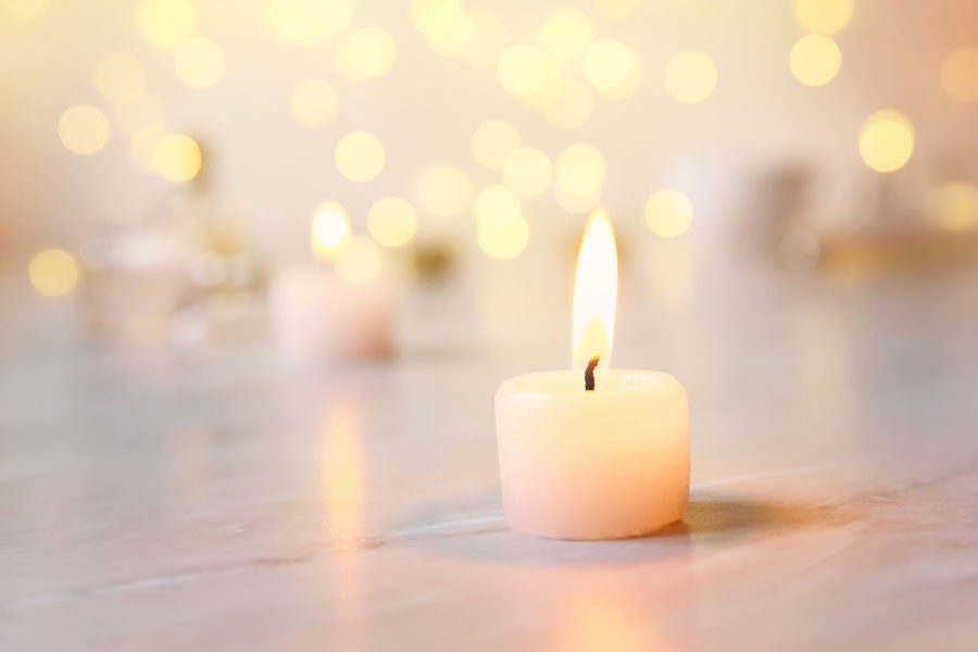 A single white tealight candle with a bright flame